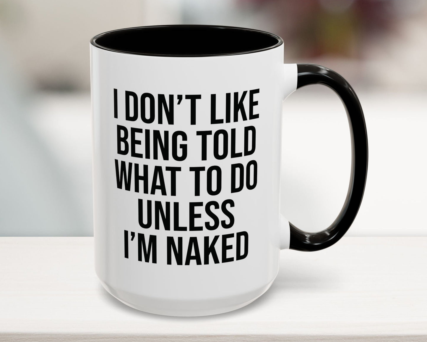 Mug with text 'I don't like being told what to do unless I'm naked' on a blurred background