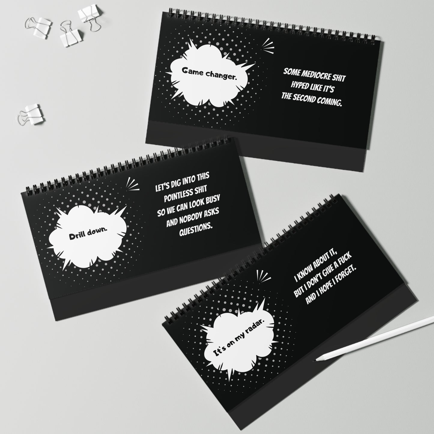 Black spiral-bound pages with white text and comic book-style speech bubbles on a gray background.
