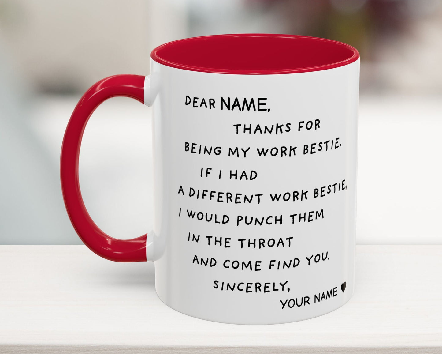 White mug with red interior and handle, featuring a humorous message on a blurred background.