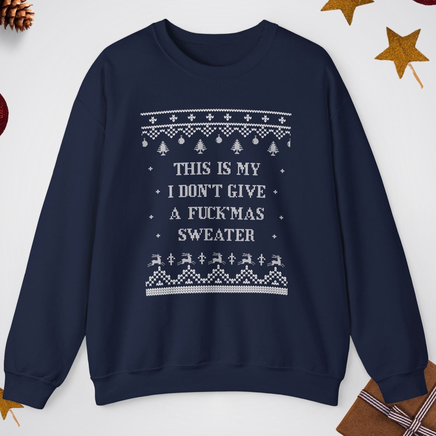 Navy blue sweater with white text and patterns on a light gray background with Christmas decorations.