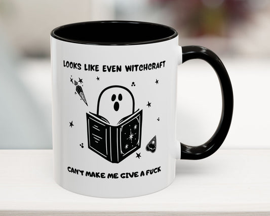 Mug with ghost reading a book design and text on a white surface.