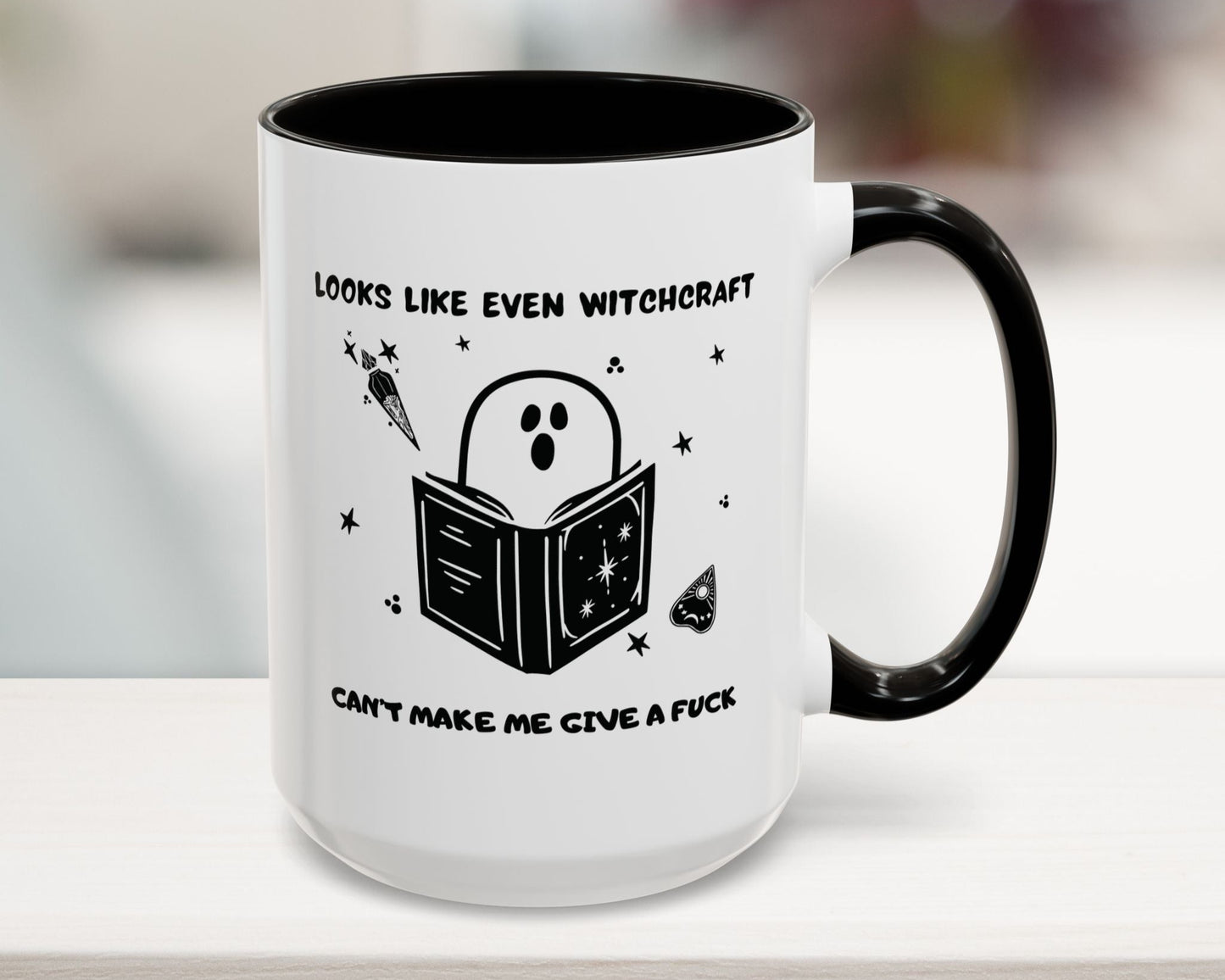 White mug with black interior and handle, featuring a ghost reading a book graphic and text.