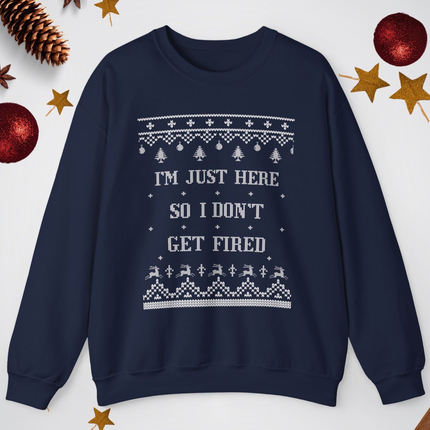 Navy blue sweatshirt with text 'I'm just here so I don't get fired' on a white background with Christmas decorations.