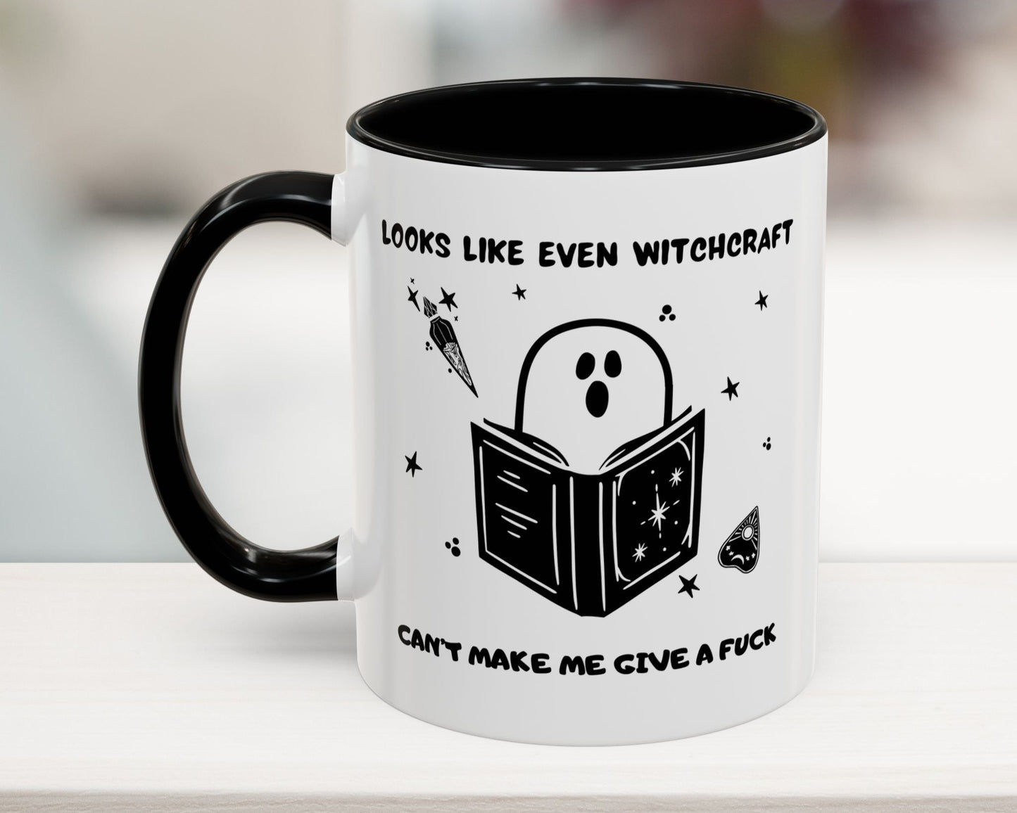 Mug with ghost reading a book design and text on a white surface.