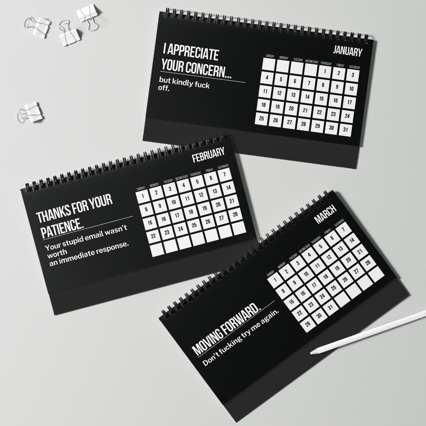 Three black spiral-bound calendars with white text on a gray background