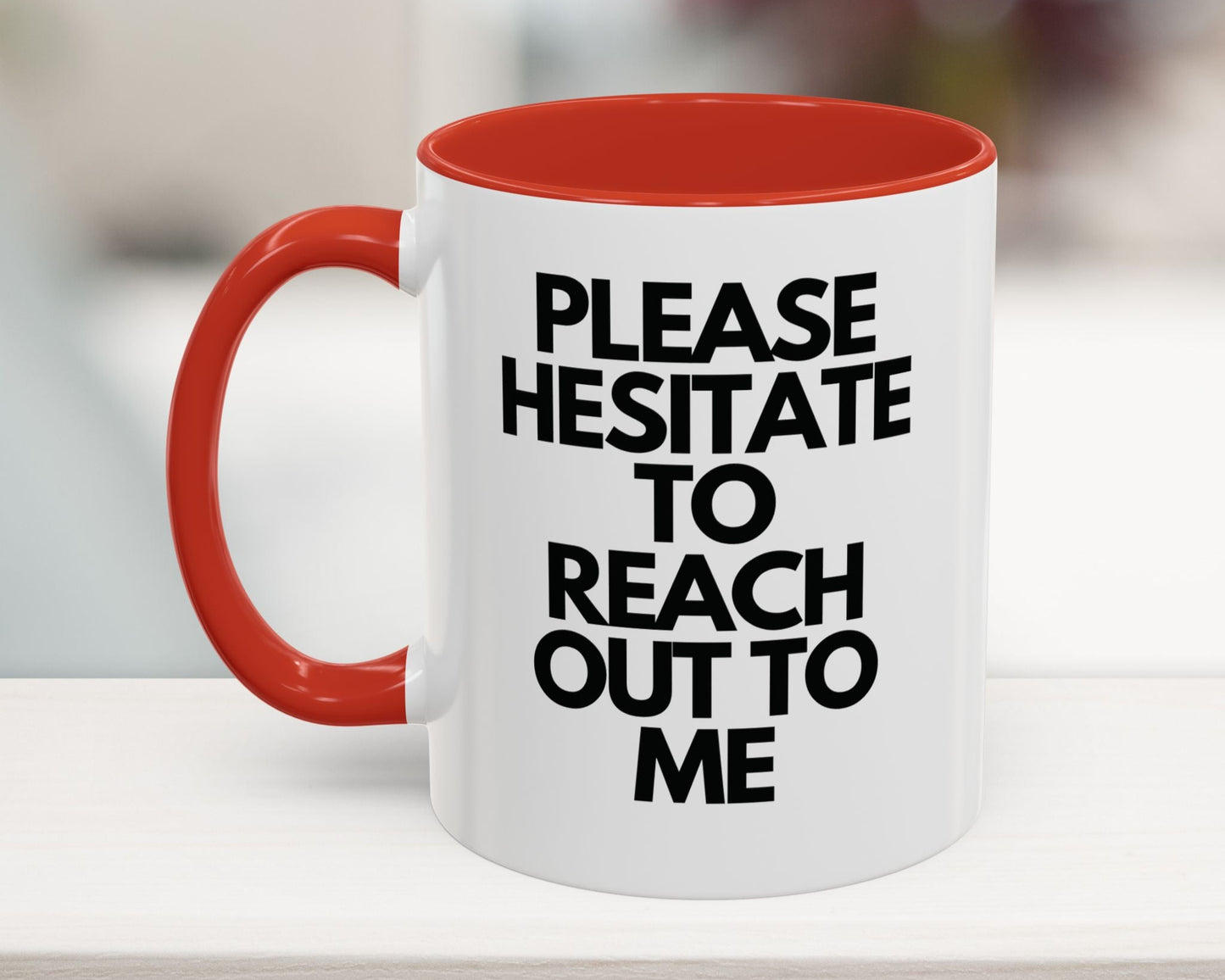 White mug with red interior and handle, featuring black text on a blurred background
