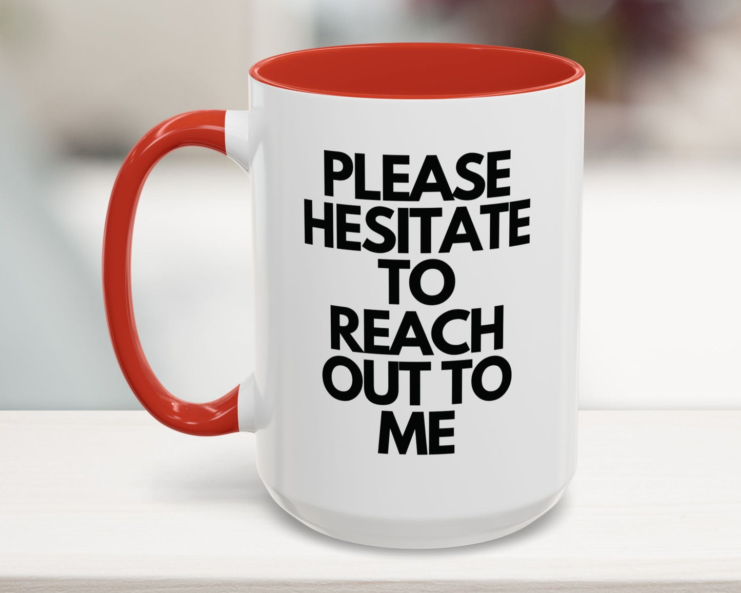 White mug with red interior and handle, featuring black text on a blurred background
