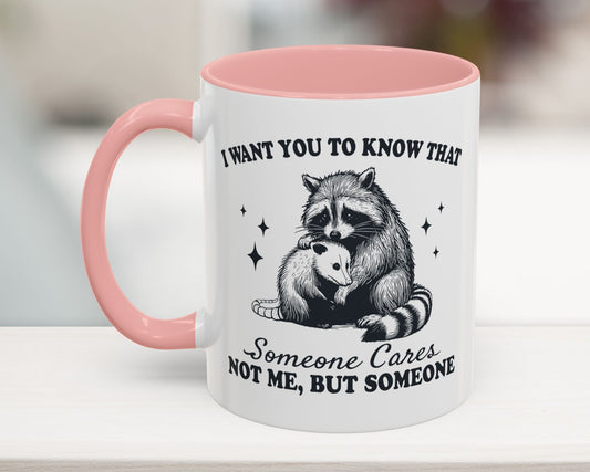 Pink 11oz mug with raccoon hugging possum, text: ‘Someone Cares (Not Me)’