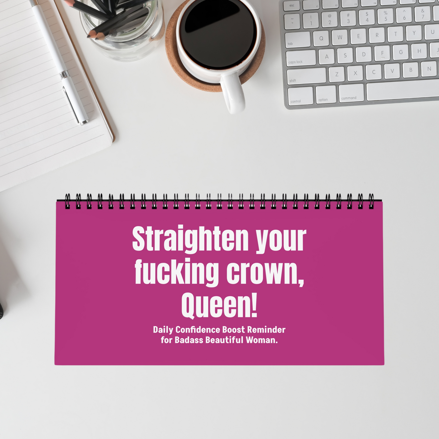 Flip desk sign in pink reading ‘Straighten Your F*cking Crown’ on a work desk