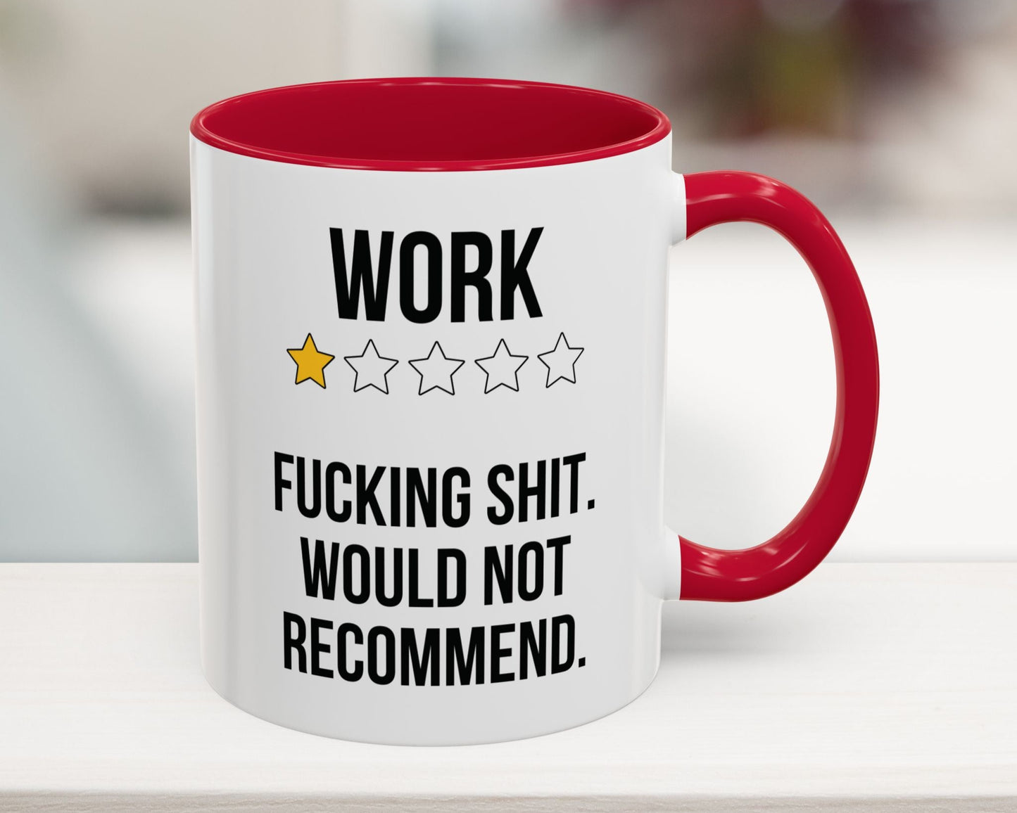 Mug with red interior and handle featuring text and star ratings on a blurred background
