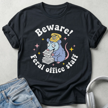 Black t-shirt with a cartoon rat design and text 'Beware! Feral office staff' on a gray background.