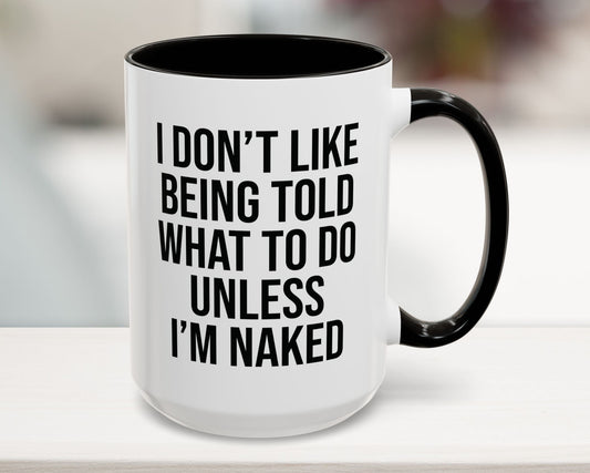 Mug with text 'I don't like being told what to do unless I'm naked' on a blurred background