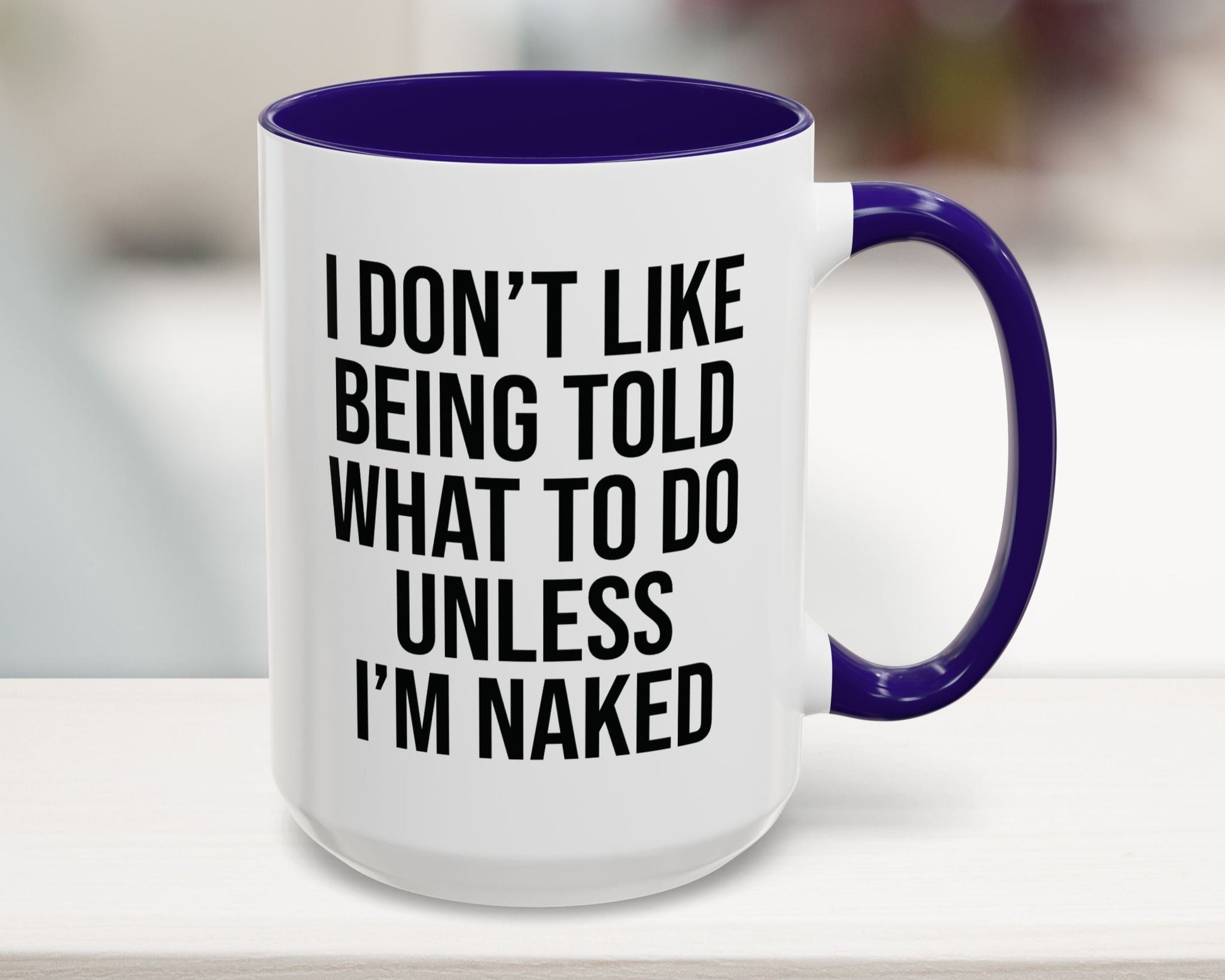 White mug with purple handle and interior, featuring a humorous quote on a blurred background