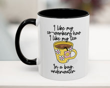 White mug with black handle featuring a yellow cartoon cup and humorous text on a blurred background