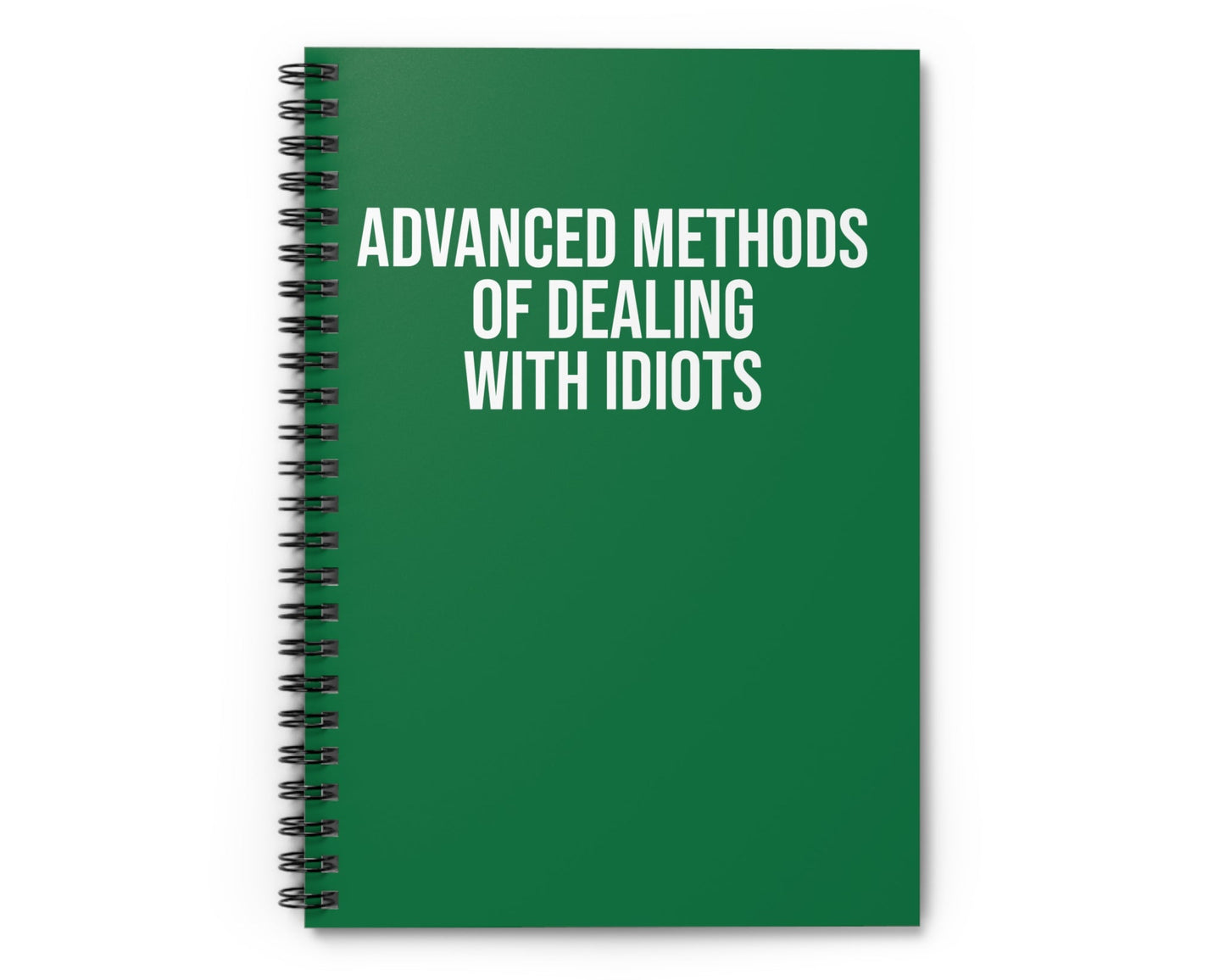 Green notebook with text 'Advanced Methods of Dealing with Idiots' on a white background