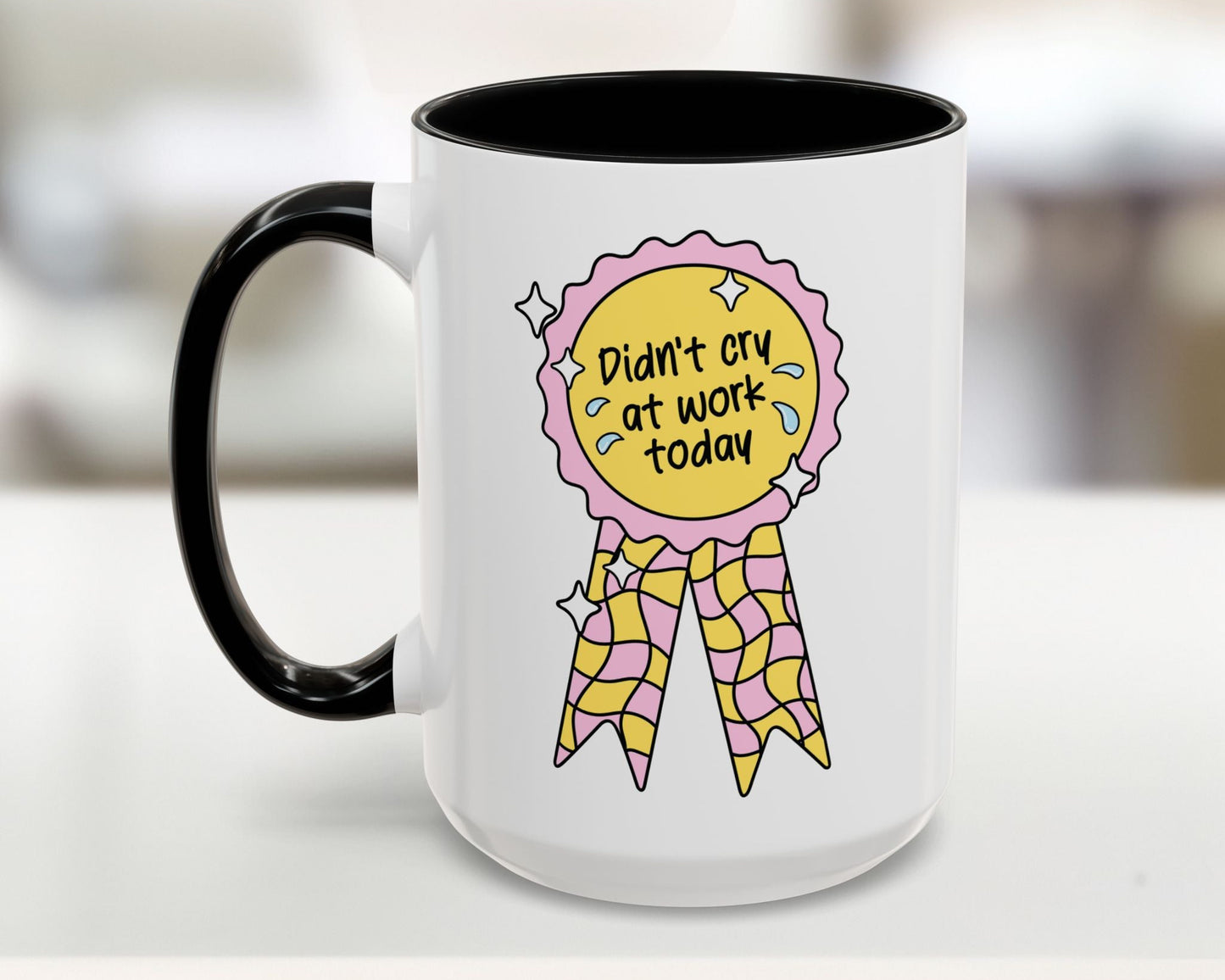 White mug with black handle featuring a colorful design and text on a blurred background