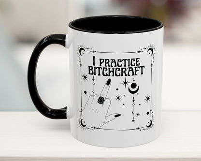 Mug with 'I Practice Bitchcraft' text and black handle on a white surface.
