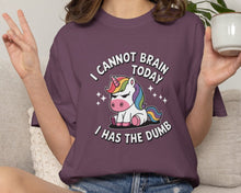 Person wearing a purple t-shirt with a unicorn graphic and text, sitting on a couch holding a mug.
