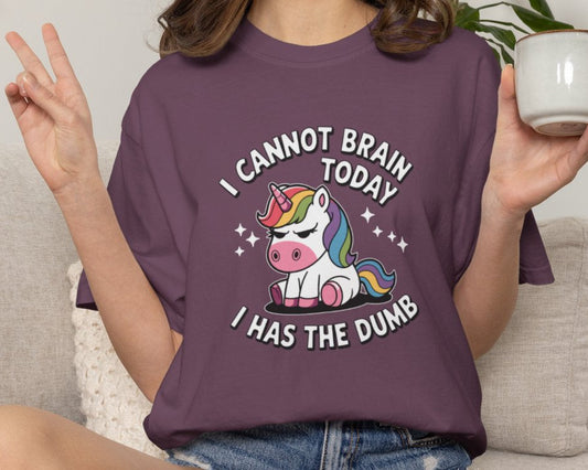 Person wearing a purple t-shirt with a unicorn graphic and text, sitting on a couch holding a mug.