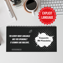 Notebook with humorous text on a desk with a coffee cup and keyboard.