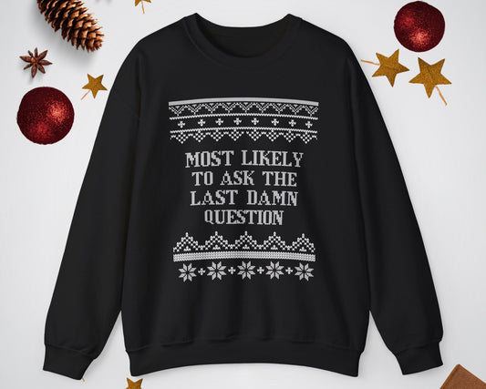 Black sweater with text 'Most likely to ask the last damn question' on a white background with Christmas decorations.