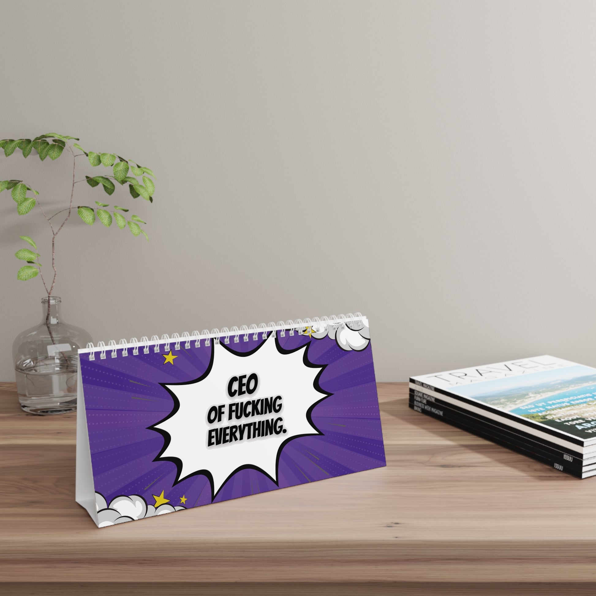Desk sign with a humorous quote on a wooden surface with a plant and books in the background.