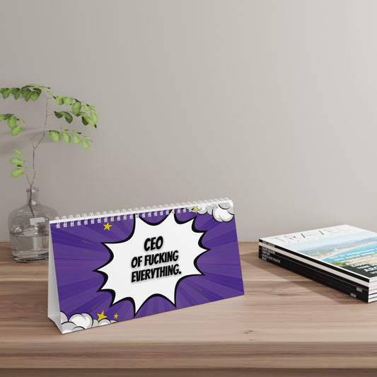 Desk sign with a humorous quote on a wooden surface with a plant and books in the background.