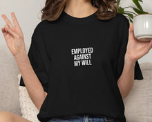Person wearing a black t-shirt with 'EMPLOYED AGAINST MY WILL' text, sitting on a couch holding a mug.