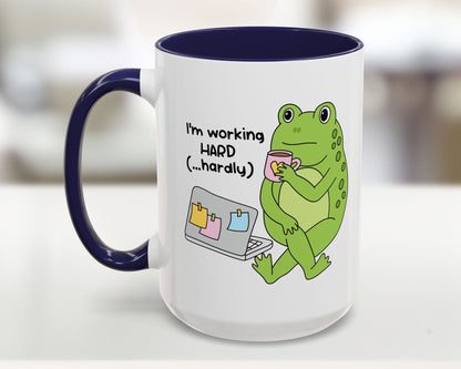 Mug with a green frog holding a cup and text 'I'm working HARD (...hardly)' on a white background