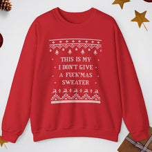Red sweater with white text and patterns on a light gray background with Christmas decorations.