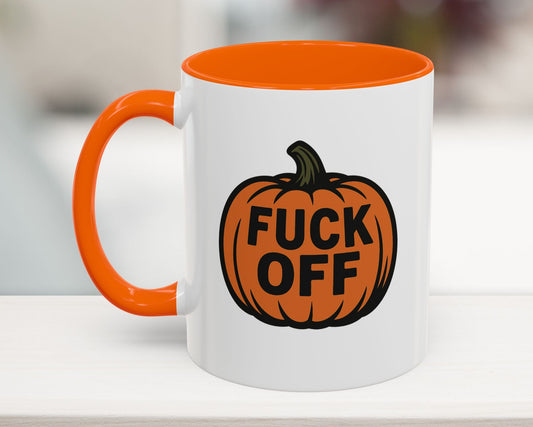 Mug with pumpkin design and 'FUCK OFF' text on a blurred background