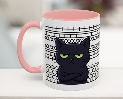 Mug with a black cat design and pink handle on a blurred background