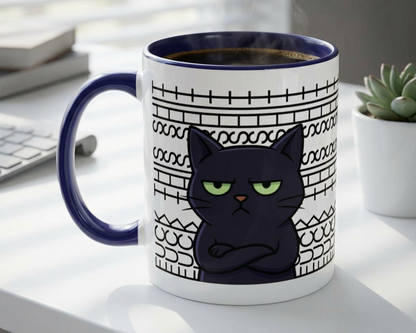 Mug with a black cat design on a desk with a keyboard and plant.