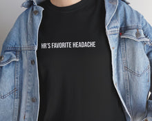 Person wearing a black t-shirt with text and a denim jacket indoors.