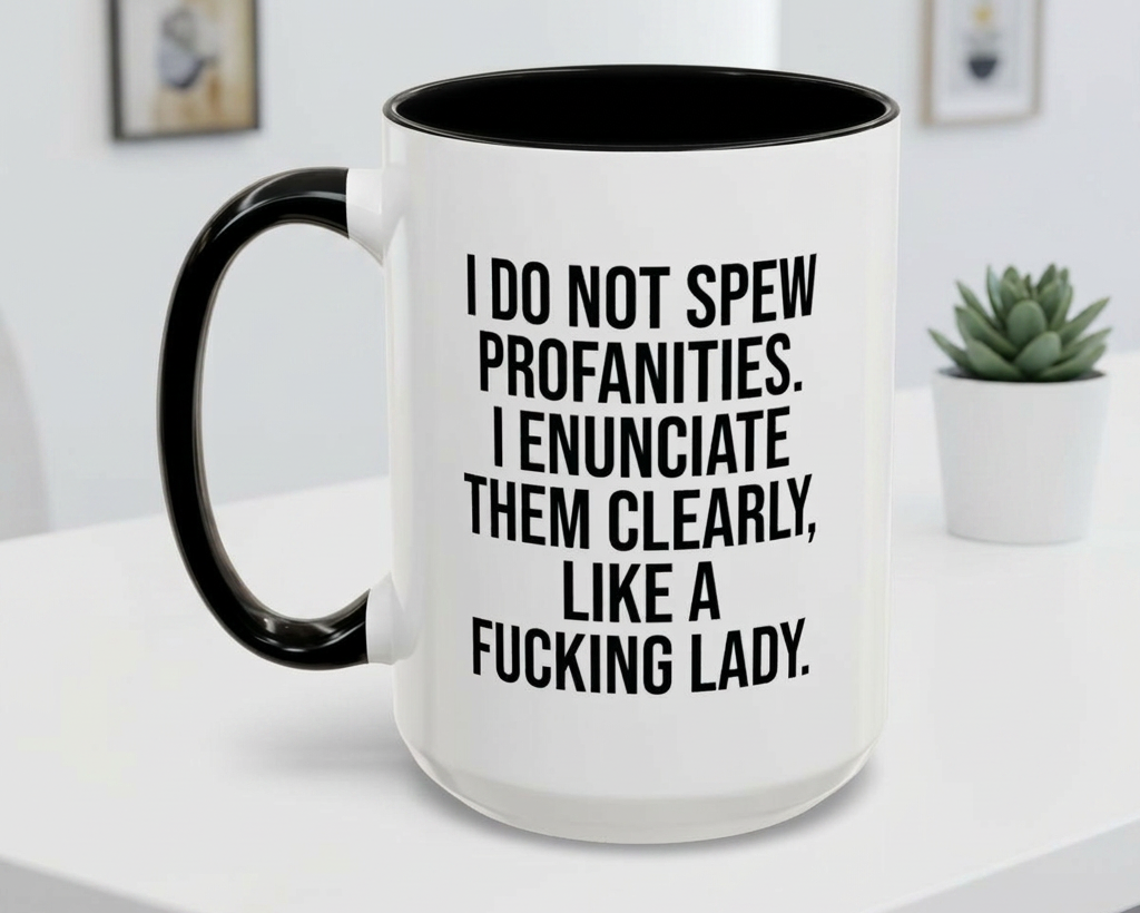 White mug with black interior and handle, featuring text on a white surface with a plant in the background.