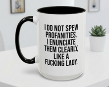 White mug with black interior and handle, featuring text on a white surface with a plant in the background.