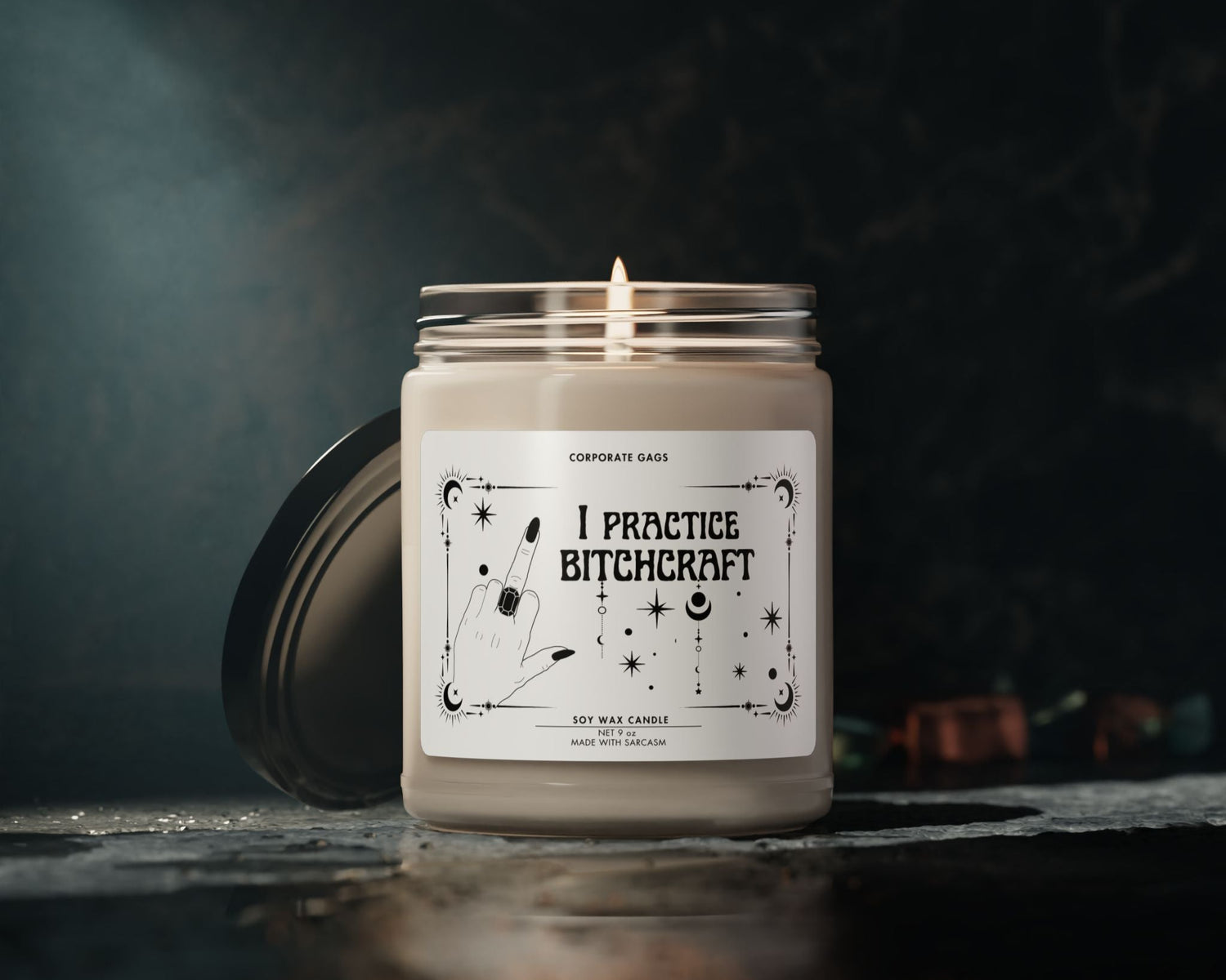 Candle in a jar with a label reading 'I Practice Bitchcraft' on a dark background