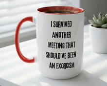 White mug with red interior and handle, featuring text on a light surface with a plant in the background.