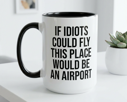 White mug with black interior and handle, featuring text on a white surface with a plant in the background.