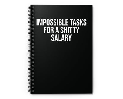 Black spiral-bound notebook with white text on a white background