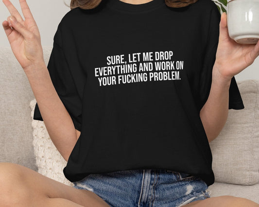 Person wearing a black t-shirt with printed text, sitting on a couch holding a mug.