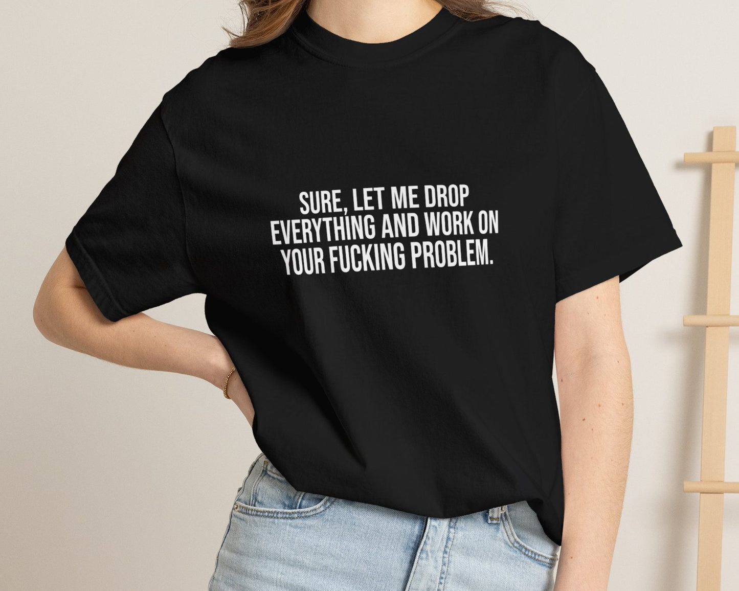 Person wearing a black t-shirt with text, standing against a neutral background.