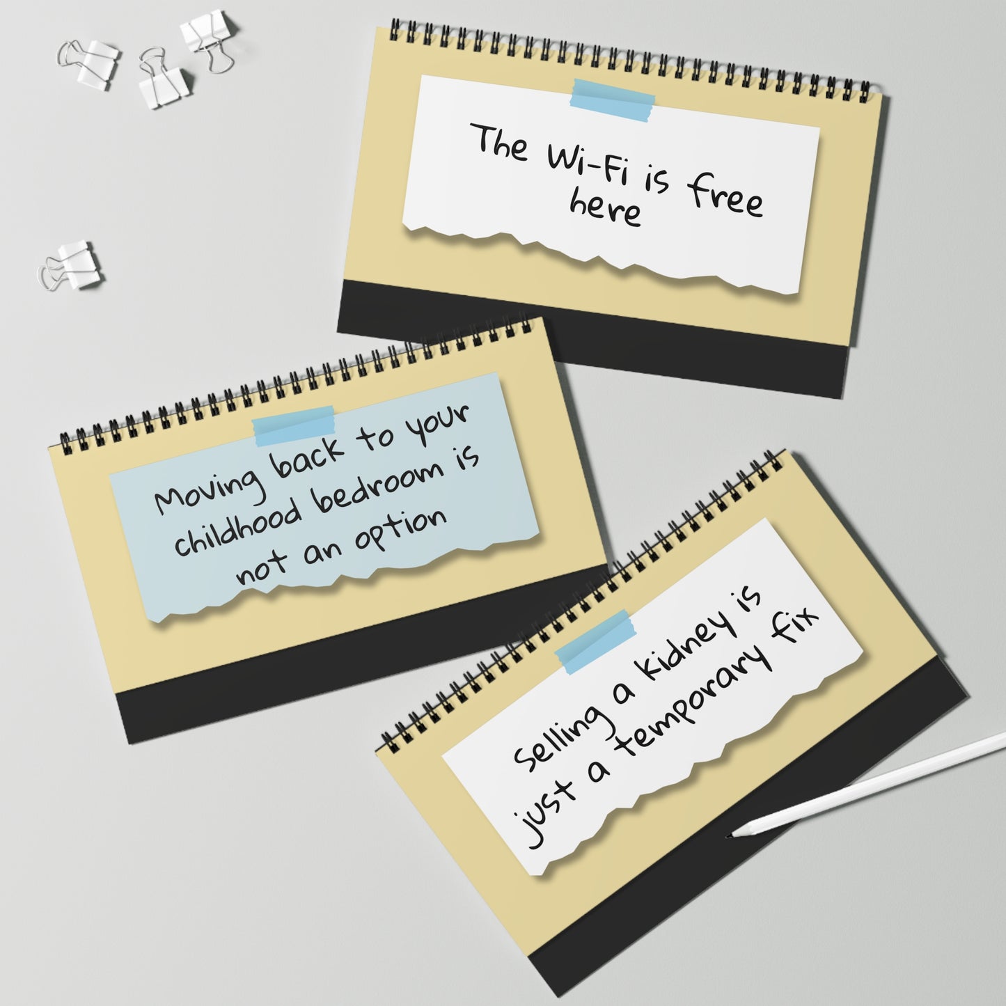 Three spiral-bound notepads with humorous text on a light gray background