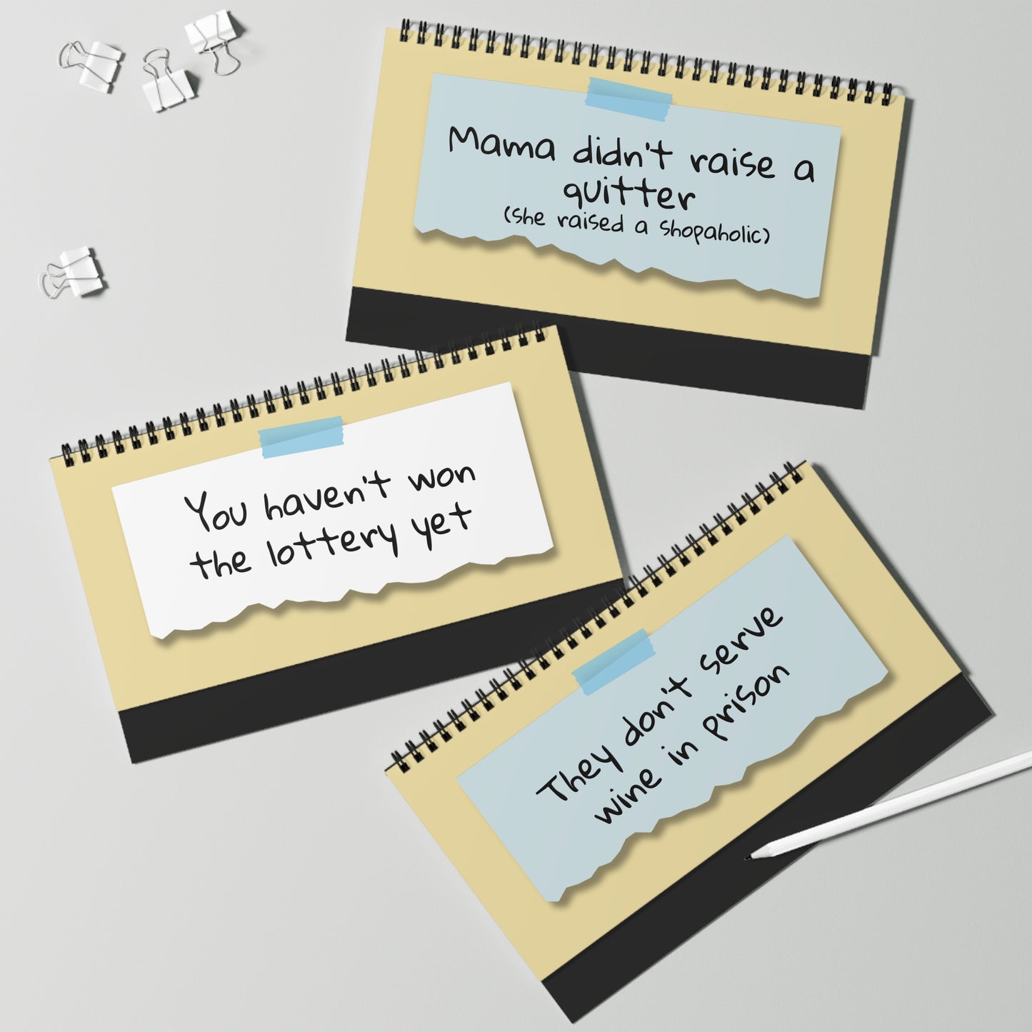 Three spiral-bound notebooks with humorous sayings on a light gray background