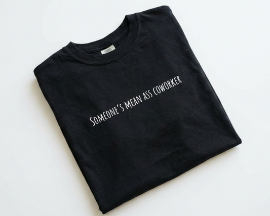 Folded black t-shirt with white text on a light gray background