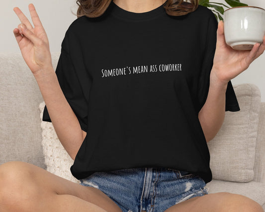 Person wearing a black t-shirt with text, sitting on a couch holding a mug.