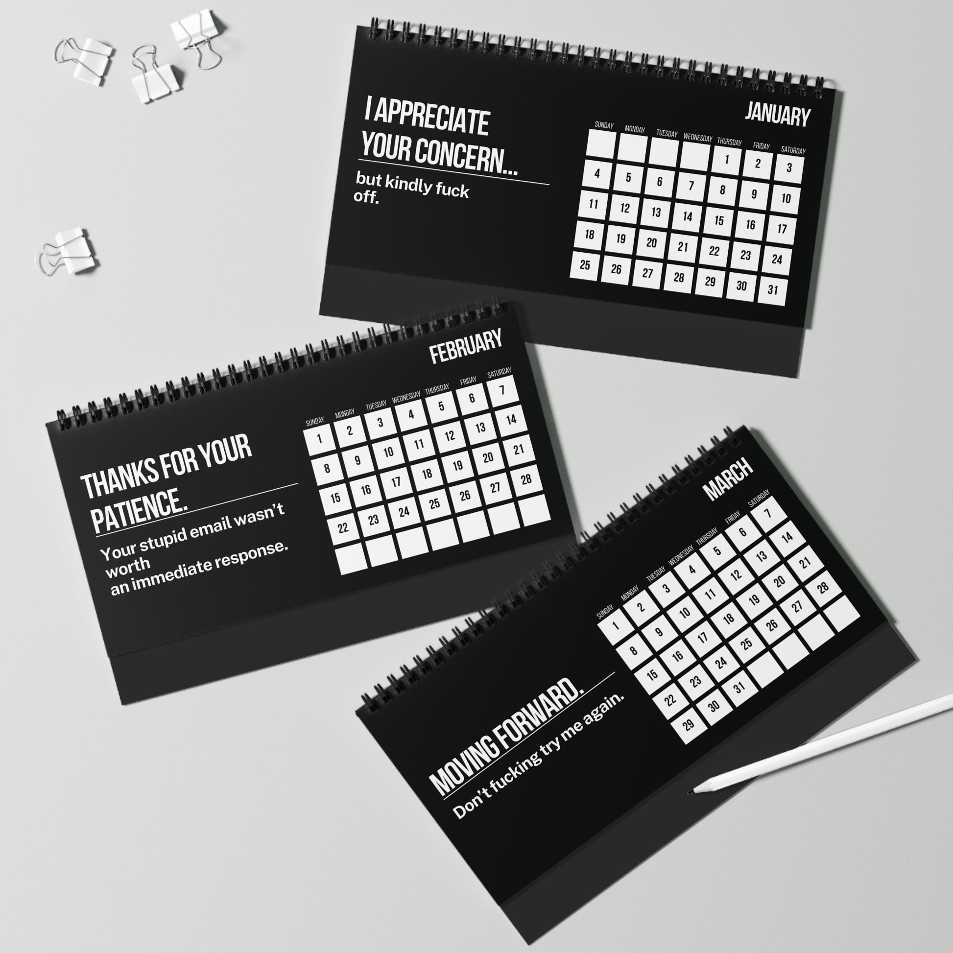 Three black spiral-bound calendars with white text on a gray background