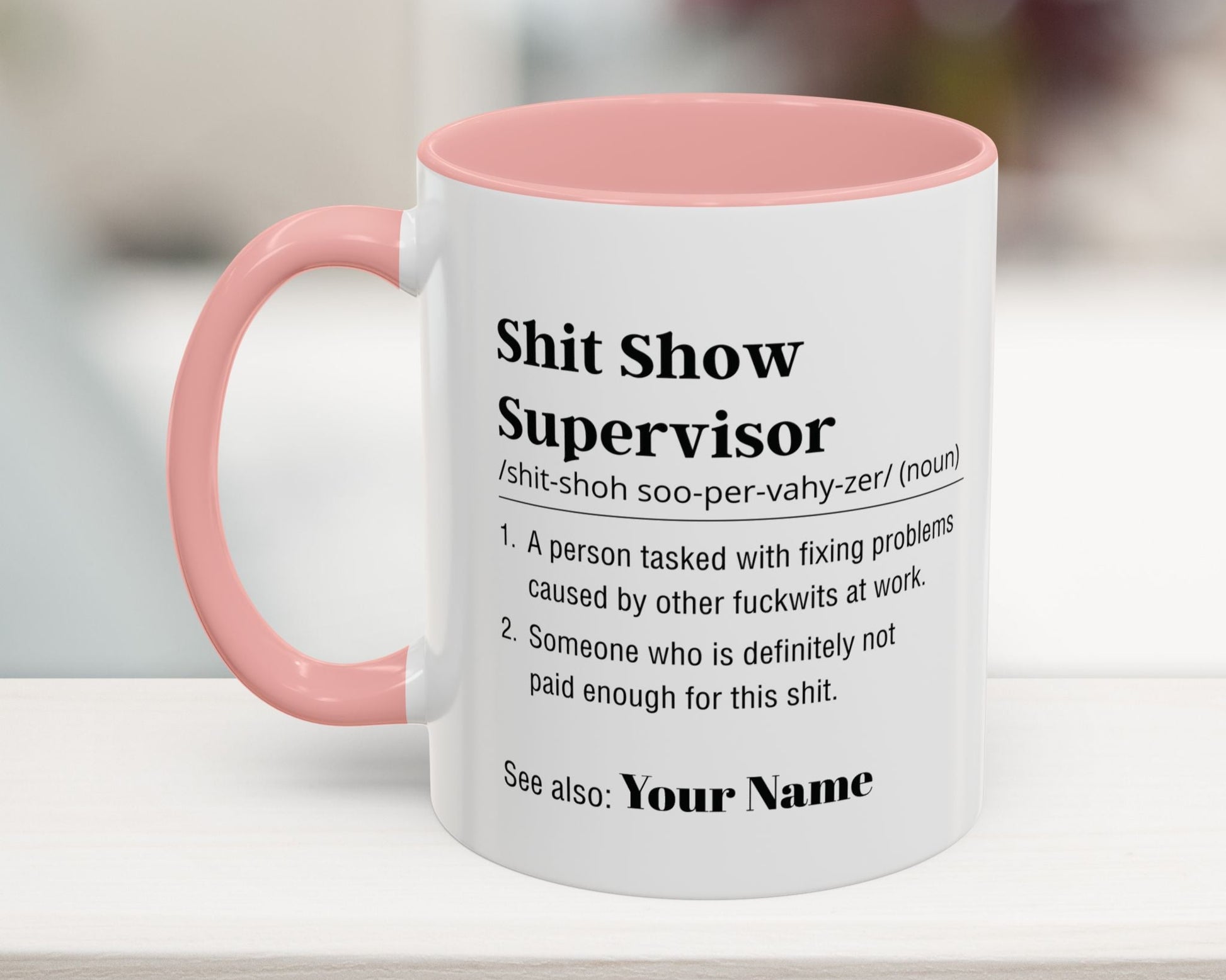 Mug with pink interior and handle featuring humorous definition text on a blurred background