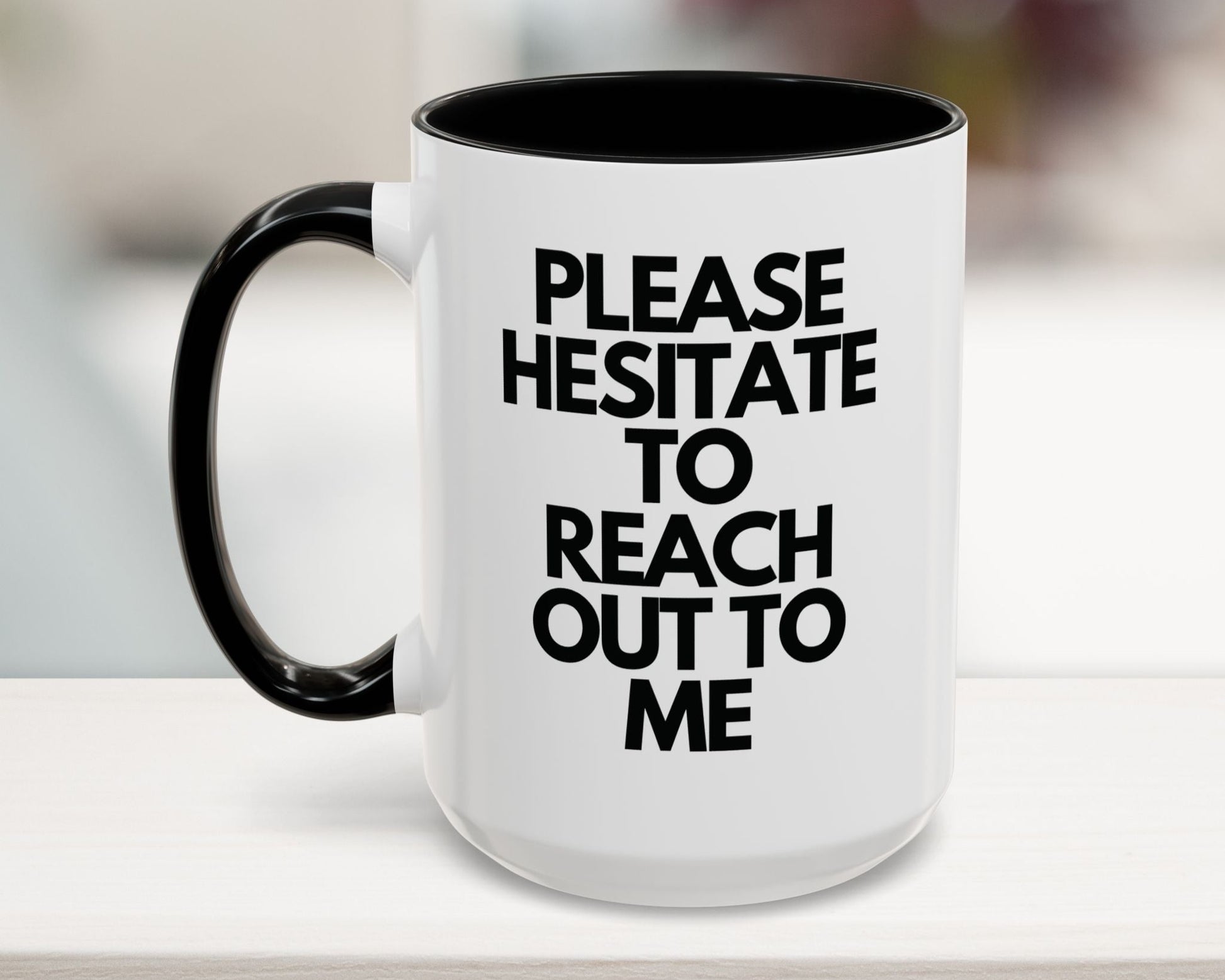 White mug with black interior and handle, featuring text on a blurred background