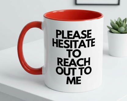 White mug with red interior and handle, featuring text on a white surface with a plant in the background.